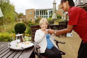 Patient being served aft tea on patio