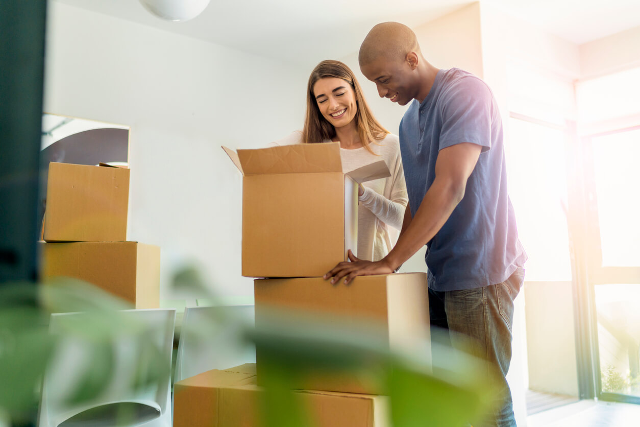 Smiling couple unpacking boxes in new house