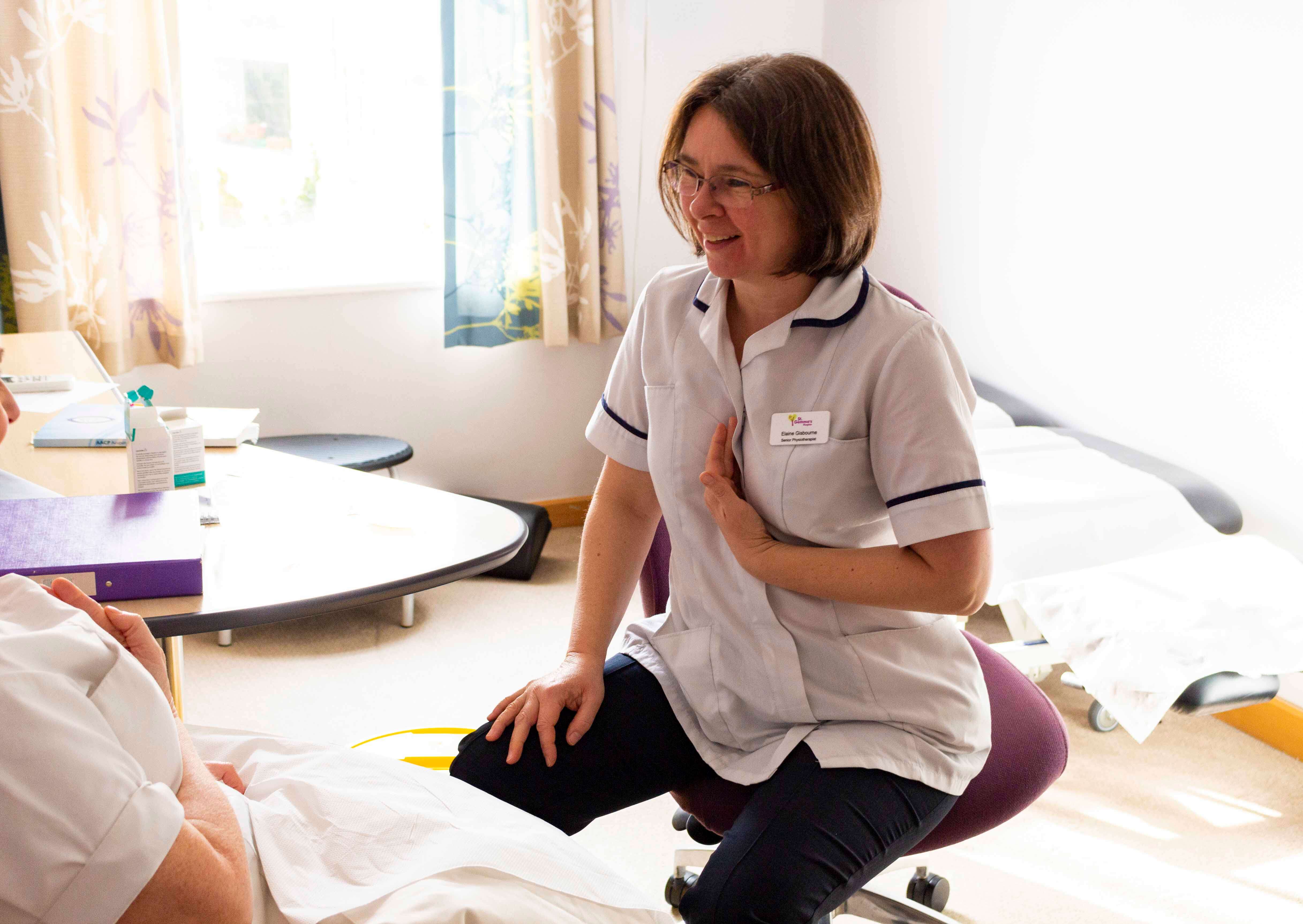 Smiling physiotherapist demonstrating an exercise to a patient
