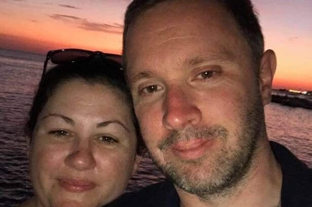 Close up of a smiling man and woman with a sunset in the background